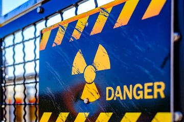 Warning sign indicates radiation hazard at industrial facility with caution stripes in midday...