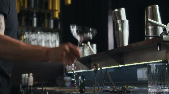 Low angle view of anonymous tattooed barman preparing cocktails at modern bar counter