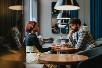 Two individuals discussing business matters in a modern and cozy cafe environment.