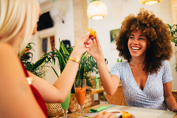 Two cheerful young women sharing a snack, enjoying a meal in a restaurant