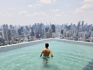 young man enjoying life at a rooftop pool high above the city skyline in Bangkok thailand