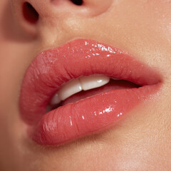 Glossy peach pink lips glisten with radiant shine, showcasing smooth and hydrated appearance. close up highlights beauty and allure of well cared for lips, perfect for any makeup look