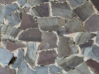 An irregular mosaic pattern of natural stone pavers in various shades of gray and brown, forming a textured background.