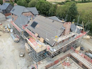 Aerial view of a partially complete detached home roof showing an installed solar panel. Other...