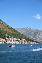 boats in the Bay of Kotor, a sailboat and a boat sailing against the backdrop of the city of...