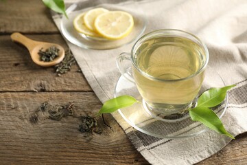 Refreshing green tea with lemon and leaves on wooden table, closeup
