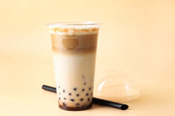 Tasty milk bubble tea in plastic cup on beige background, closeup. Space for text