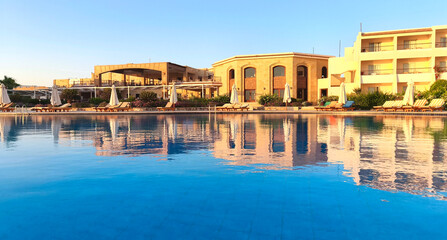A tranquil resort by the Red Sea in Egypt. The scene features a large swimming pool reflecting the...