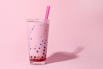 Tasty milk bubble tea in glass on pink background, space for text