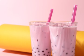 Tasty milk bubble tea in glasses on color background, closeup. Space for text