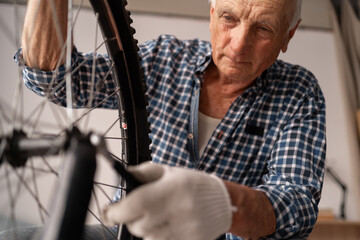 Active senior male cyclist checking bike wheel doing maintenance routine fixing with wrench....