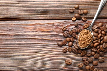 Spoon with instant coffee and beans on wooden table, flat lay. Space for text