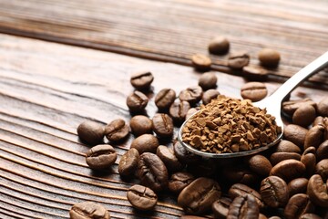 Spoon with instant coffee and beans on wooden table, closeup. Space for text