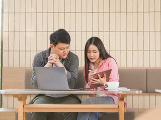 Young man and woman working or talking together in a cafe, man sitting in front of laptop, woman...