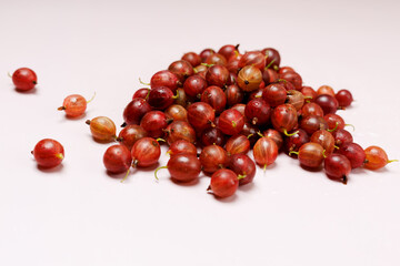 A handful of fresh gooseberries in drops of water, close-up, top view, on a light background