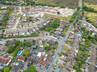 Drone view of a typical British suburban street showing both terraced and detached houses, some with large extensions and fitted solar panels to the roofs. A new housing development is beyond.