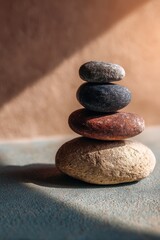 Stack of balanced stones in sunlight on textured surface