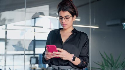 Young Indian or arabian business woman ceo manager using cell phone mobile application. Smiling Latin Hispanic businesswoman holding smartphone for finance work chat online in office. Copy space - Powered by Adobe