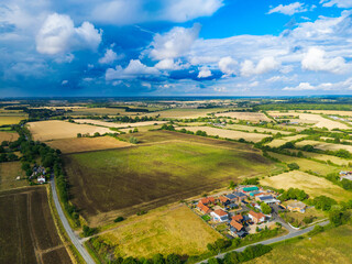Dramatic aerial view of a pre storm sky seen over rural British farmland. Note the small new housing development on the lower right.