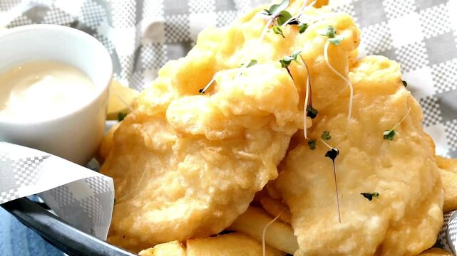 Golden fried fish and chips served with tartar sauce on a tray