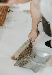 A builder man sweeps up construction debris with a broom.