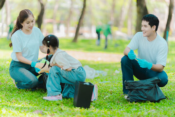 Asian family on summer vacation, parents teaching children to pick up plastic bottles and trash in...