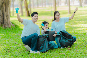 Asian family on summer vacation, parents teaching children to pick up plastic bottles and trash in...
