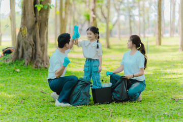 Asian family on summer vacation, parents teaching children to pick up plastic bottles and trash in...