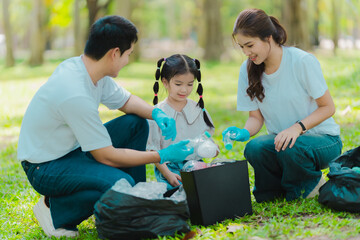 Asian family on summer vacation, parents teaching children to pick up plastic bottles and trash in...