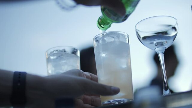 Bartender pouring drink over ice into tall glass