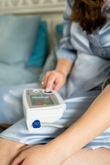 Woman pressing button on digital blood pressure monitor, starting health check, self-monitoring and...