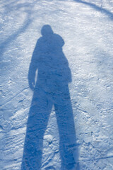 The shadow of a man on blue snow in winter