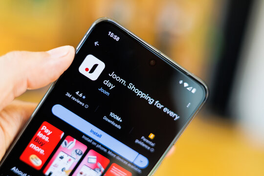 Phone in hand displaying Joom app on Google Play Store