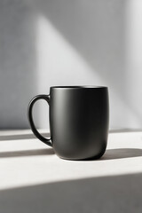 Black matte ceramic mug casting soft shadow on white table, minimalist design, modern vessel, drinkware, coffee mug, tea cup, stylish, simple interior, monochrome