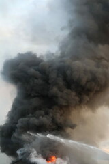 Obraz premium Gigantic, high column of black smoke raising into the sky after explosion in residential area 