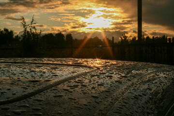 Raindrops on the roof of a car at sunset.