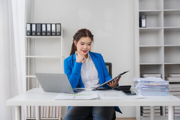 Professional Contemplation: An Asian woman dressed professionally, thoughtfully analyzing work...