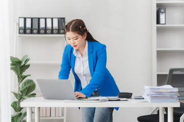 Portrait of beautiful businesswoman talking on the phone and working on laptop while sitting in...