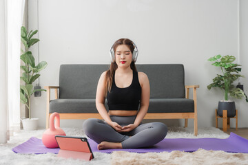 Online Yoga Class: A woman performs a side bend yoga pose on a purple mat at home, following...