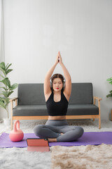 Online Yoga Class: A woman performs a side bend yoga pose on a purple mat at home, following...