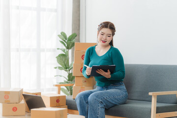 Young business woman working online e-commerce shopping at her shop. Young asia woman seller prepare parcel box of product for deliver to customer. Online selling. E-commerce.