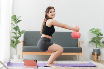 Home Workout: A young woman, beaming with determination, executes a squat with a kettlebell in a...