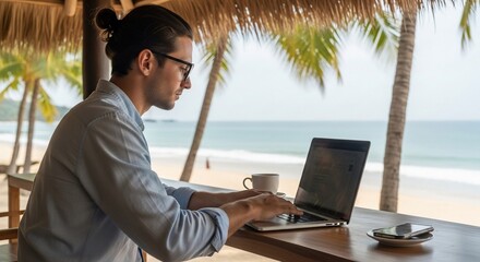 Man working remotely on laptop with ocean view from tropical beach hut