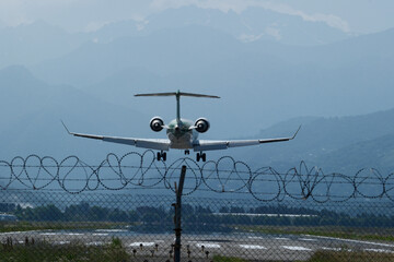 A commercial passenger jet approaches the runway for landing, captured from behind as it descends...