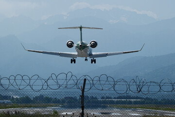 A commercial passenger jet approaches the runway for landing, captured from behind as it descends...