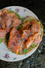 Delicious smoked salmon and avocado toast served on a floral plate with pepper seasoning