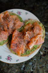 Delicious smoked salmon and avocado toast served on a decorative plate in a cozy kitchen setting