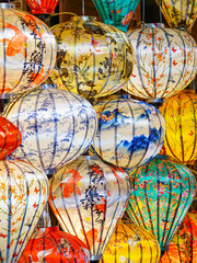 Close-up of vibrant Vietnamese silk lanterns with koi, blossoms, and calligraphy designs on display