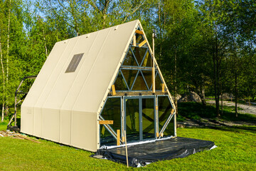Unfinished A-Frame Glamping Cabin in Forest with Exposed Frame and Glass Front Awaiting Completion