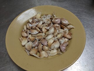 Peeled garlic cloves arranged on a tan plate.
